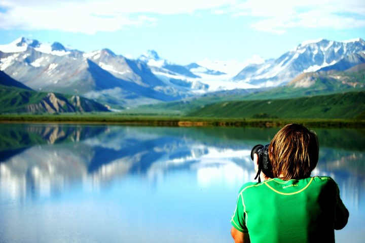 a person standing in front of water and a mountain in the background