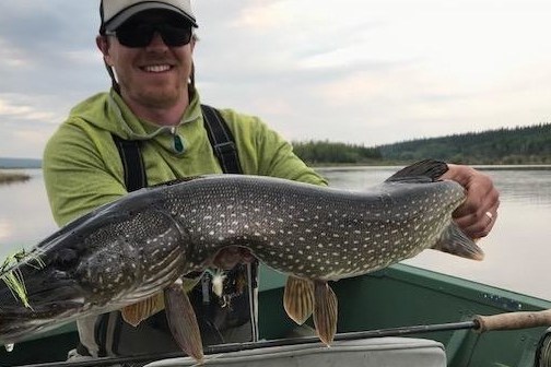 a man holding a fish on a boat in the water