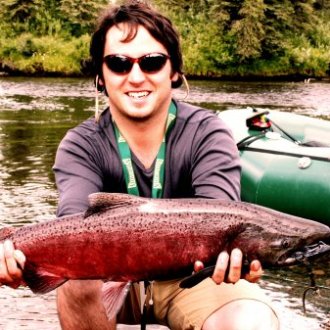 a person holding a fish in front of a body of water
