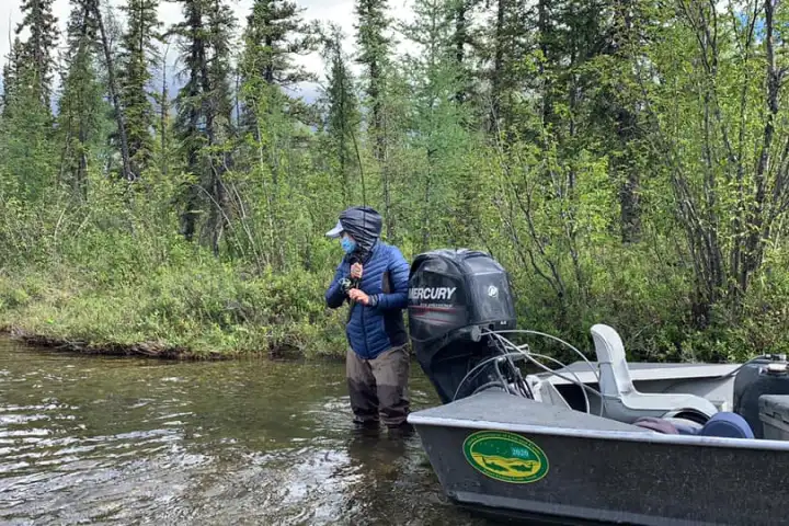 a man riding on the back of a boat next to a tree