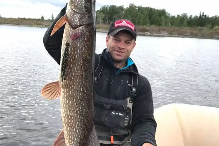 a person holding a fish on a boat in a body of water