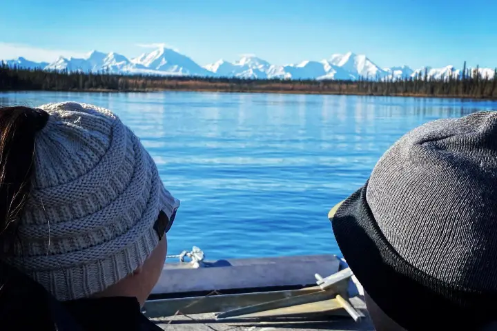 a woman sitting on a bench next to a body of water
