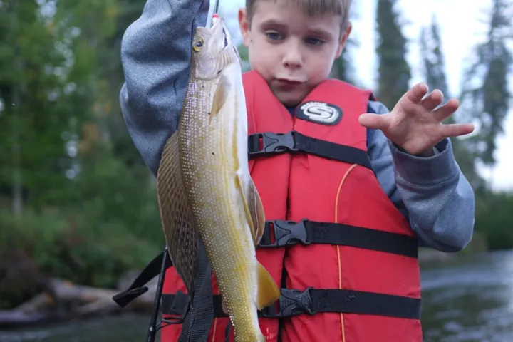 a young boy holding a fish