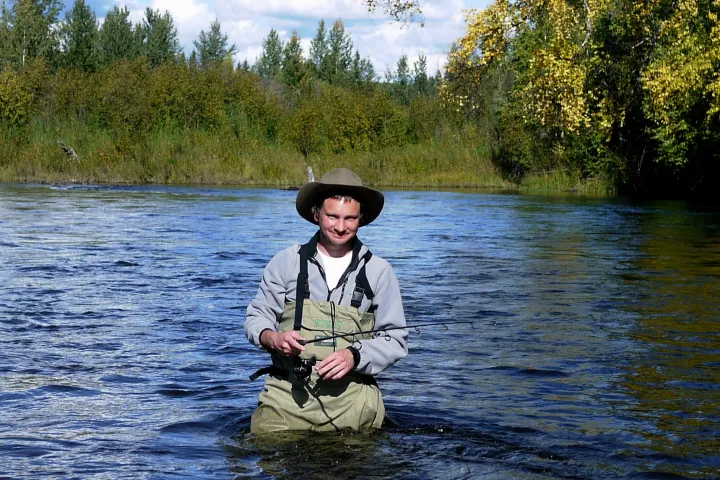 a person riding on the back of a boat next to a lake