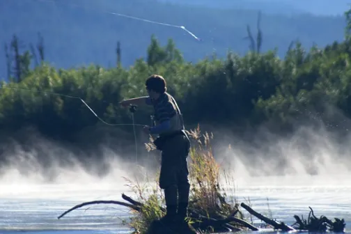 a man riding on the back of a boat in the water