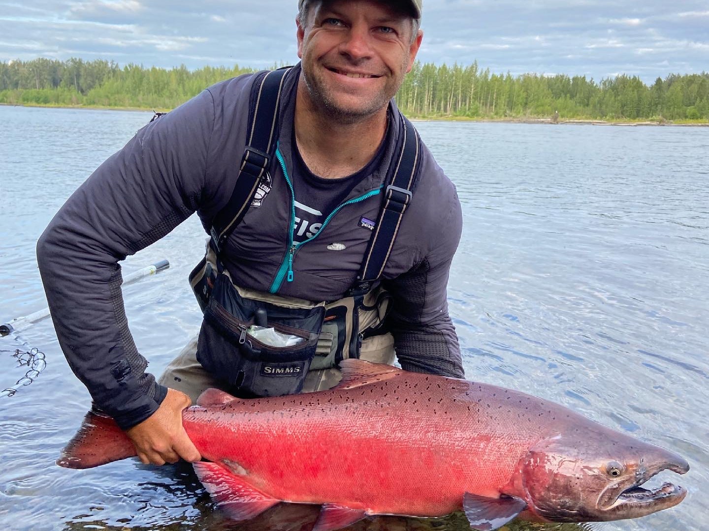 a man holding a fish on a boat in a body of water